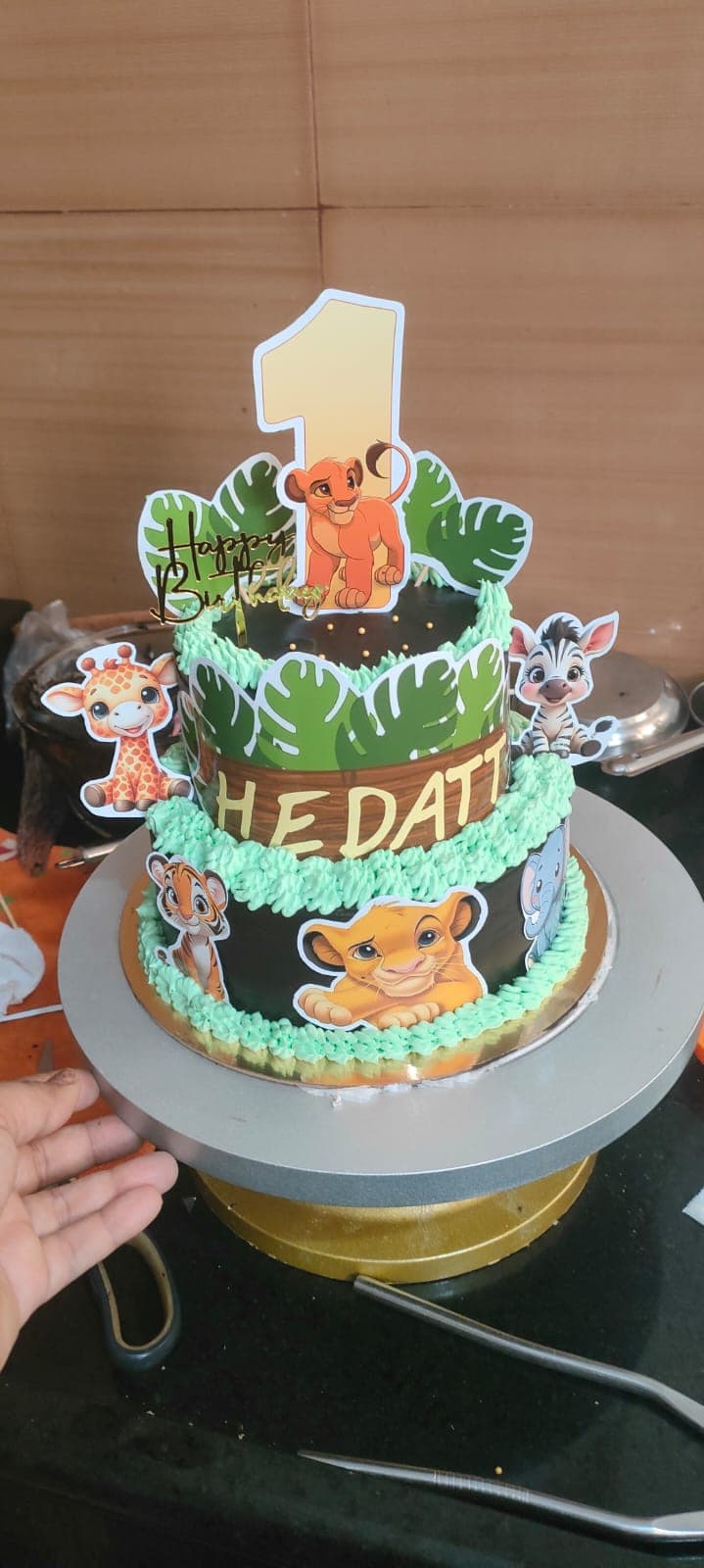A two-tier first-birthday cake with hand-piped foliage
